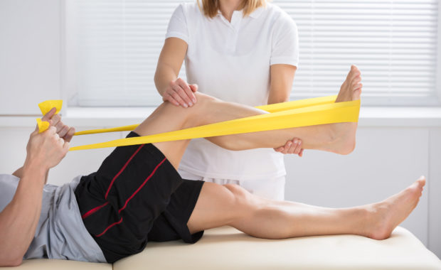 Physiotherapist Giving Treatment With Exercise Band